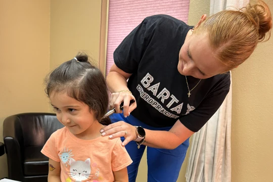 Savannah Bartay Using Adjustment Tool on Child